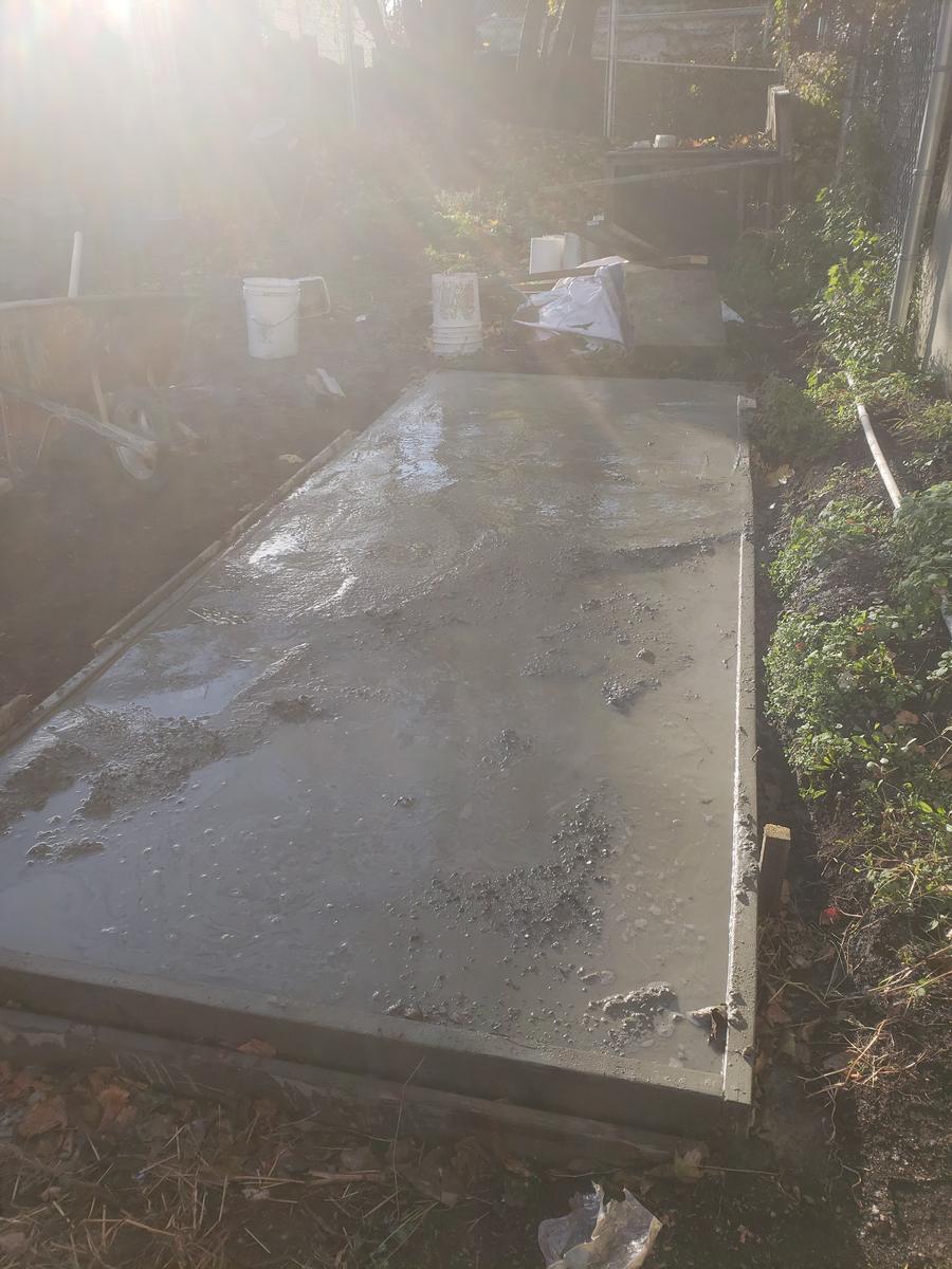 Poured concrete foundation slab for a composting bin structure at a community garden