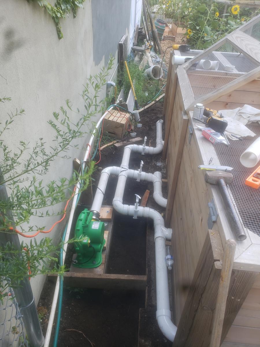 Outdoor recirculating hydroponic growing channels plumbed with PVC piping and a water pump