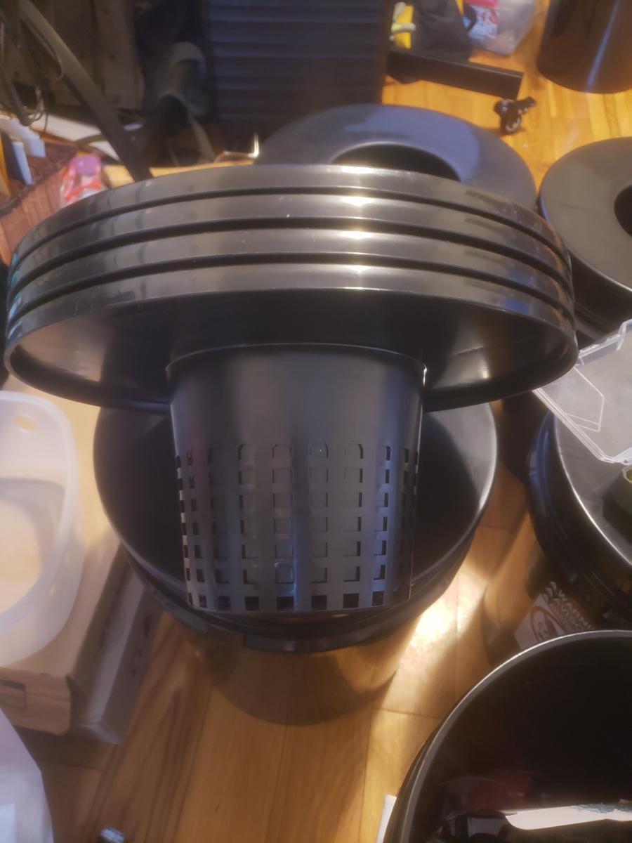 Bucket lids fitted with net-pot cutouts for a bucket-based hydroponic system, next to a pH and nutrient testing kit