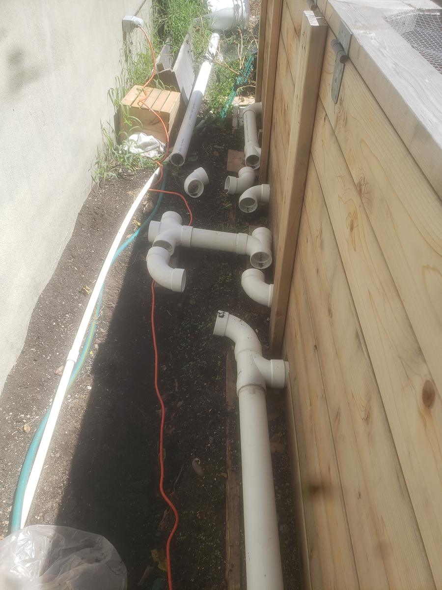 Raised garden beds with an irrigation trench and PVC supply line being laid at a community garden