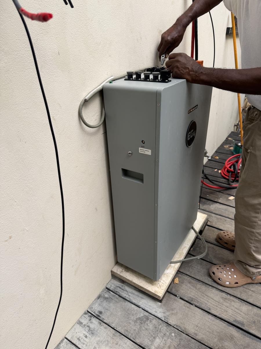 Technician wiring the top of a battery storage cabinet on site